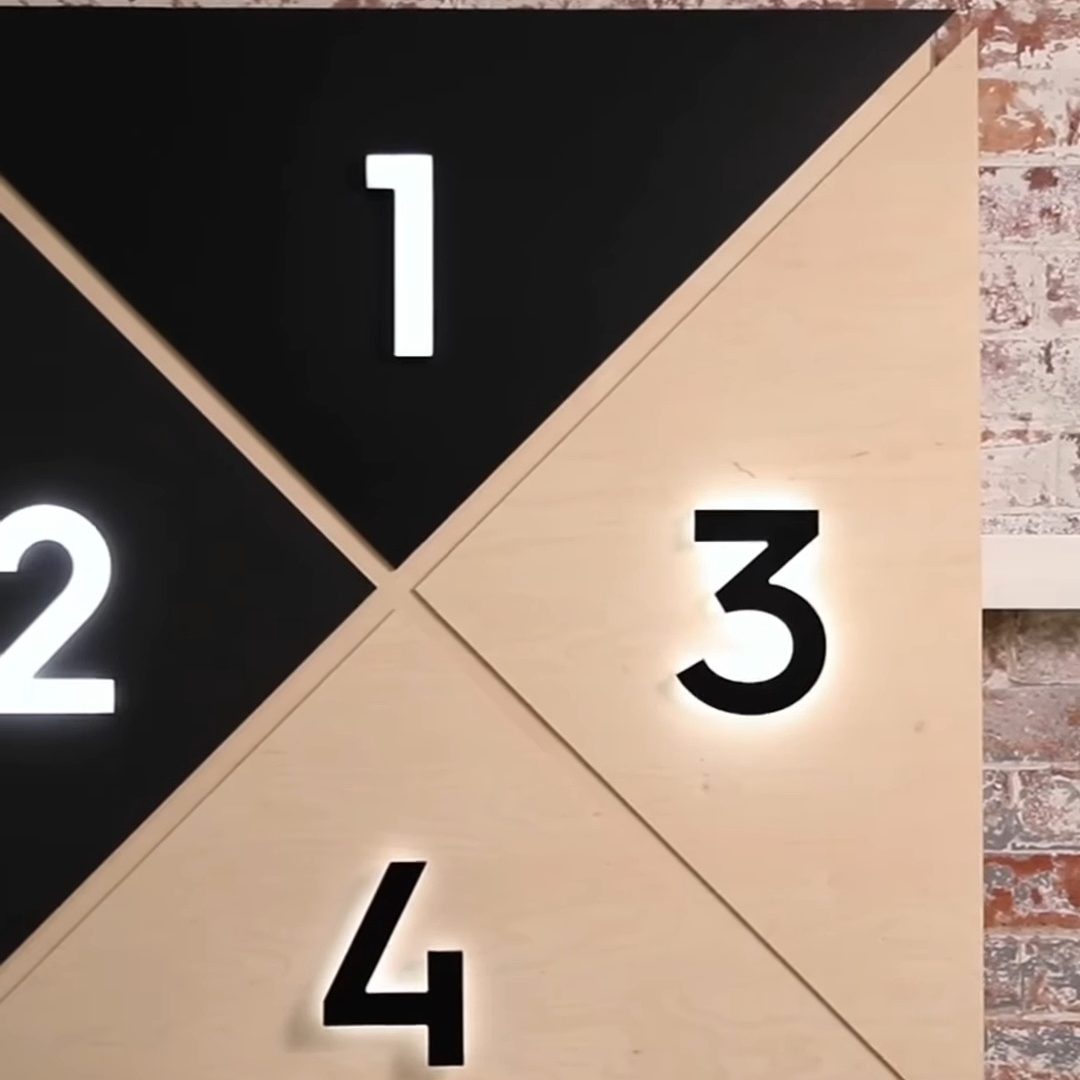 Painel em madeira e preto com os números 1, 2, 3 e 4 iluminados